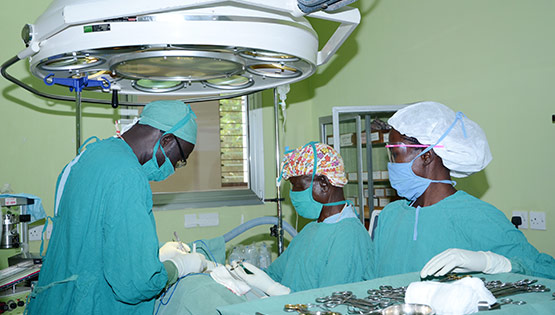 Three surgeons in scrubs perform a procedure in Lachor Hospital