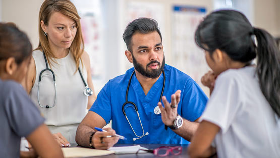 A multi ethnic group of doctors and nurses are in a meeting together